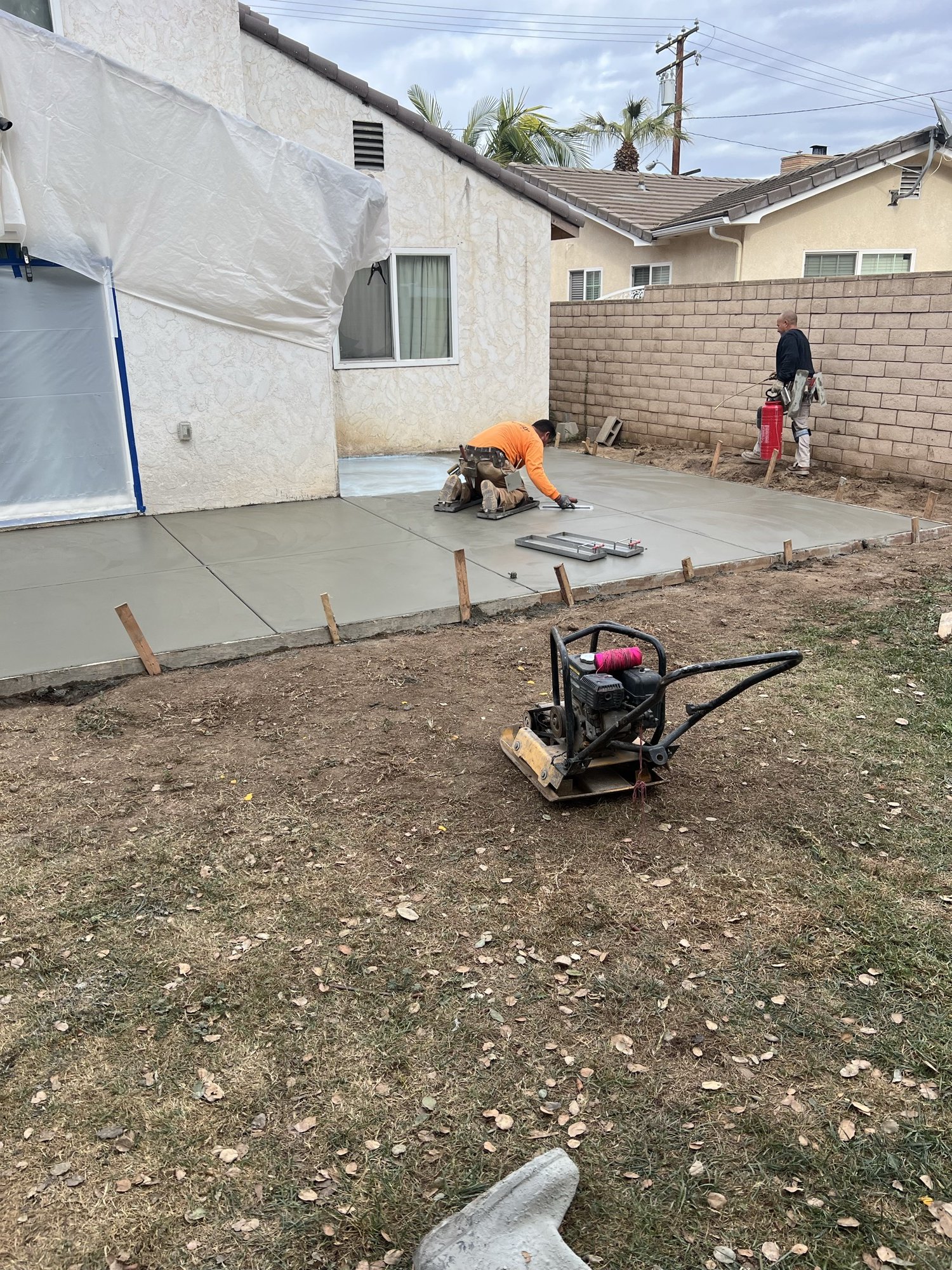 FFG concrete contractor troweling a freshly poured residential slab while a second worker finishes the edge