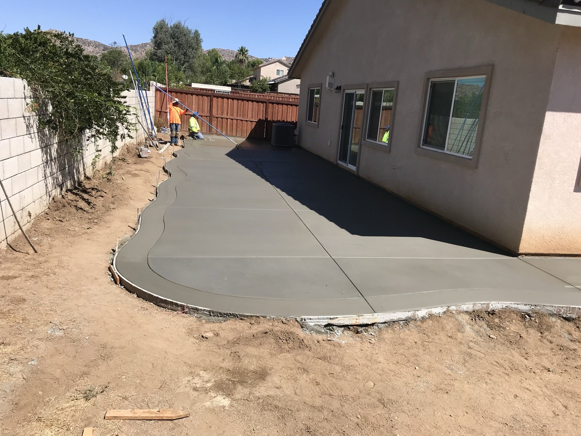 Newly poured walkway curving along a stucco wall